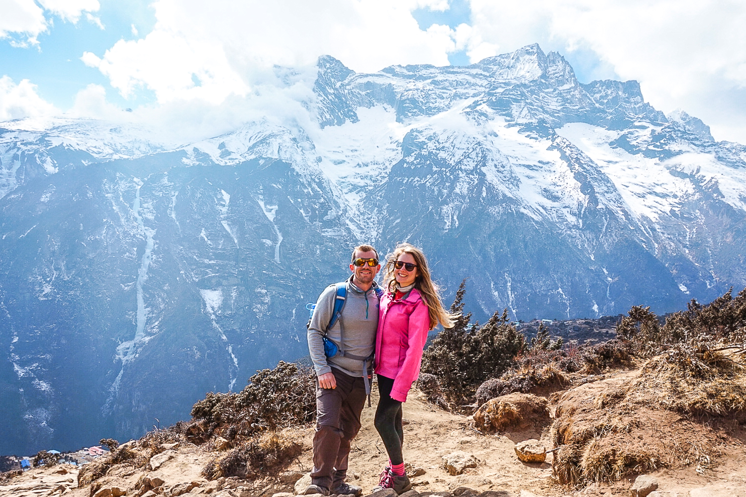 A couple stood in front of an impressive snow capped Himalayan mountain