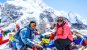 A couple at Everest Base Camp 2019 stone surrounded by prayer flags and a snow capped mountain in the background