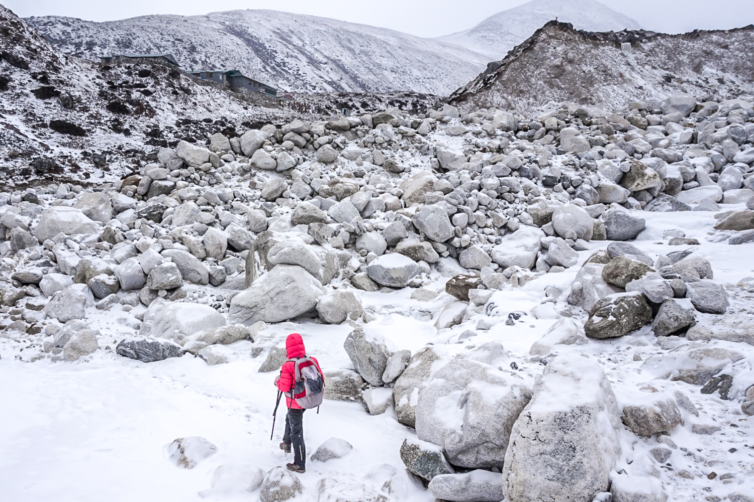 A girl trekking through a snowy, rocky terrain