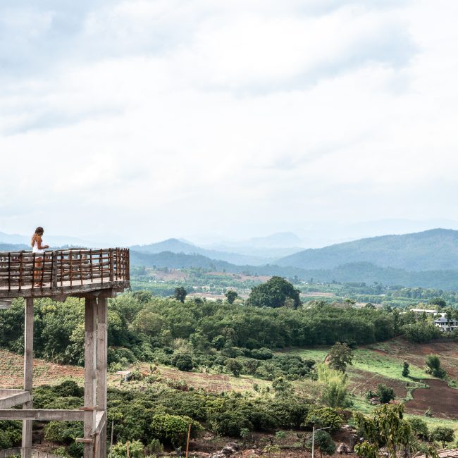 A panoramic view of the Thai countryside with a girl overlooking from a walkway
