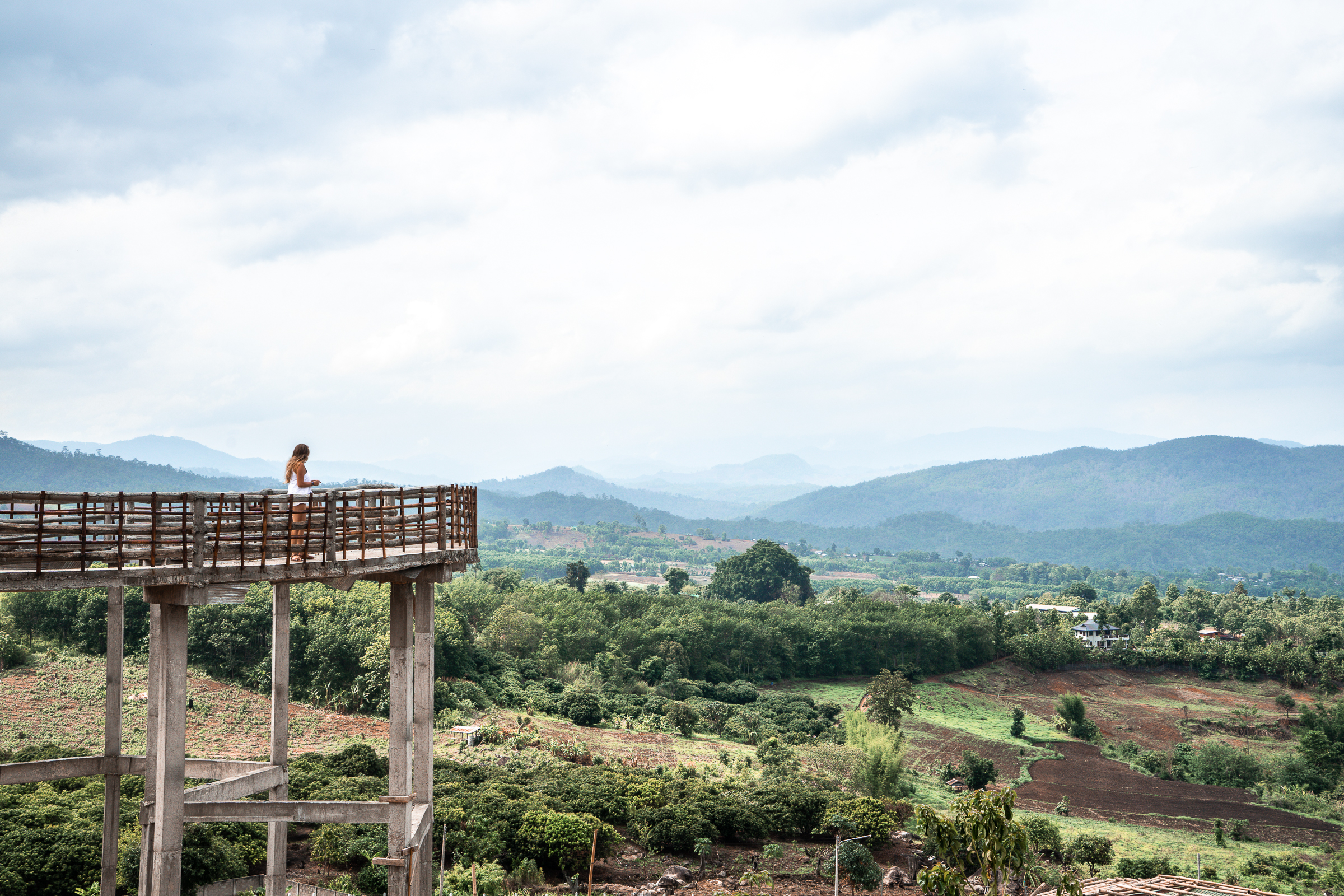 A panoramic view of the Thai countryside with a girl overlooking from a walkway