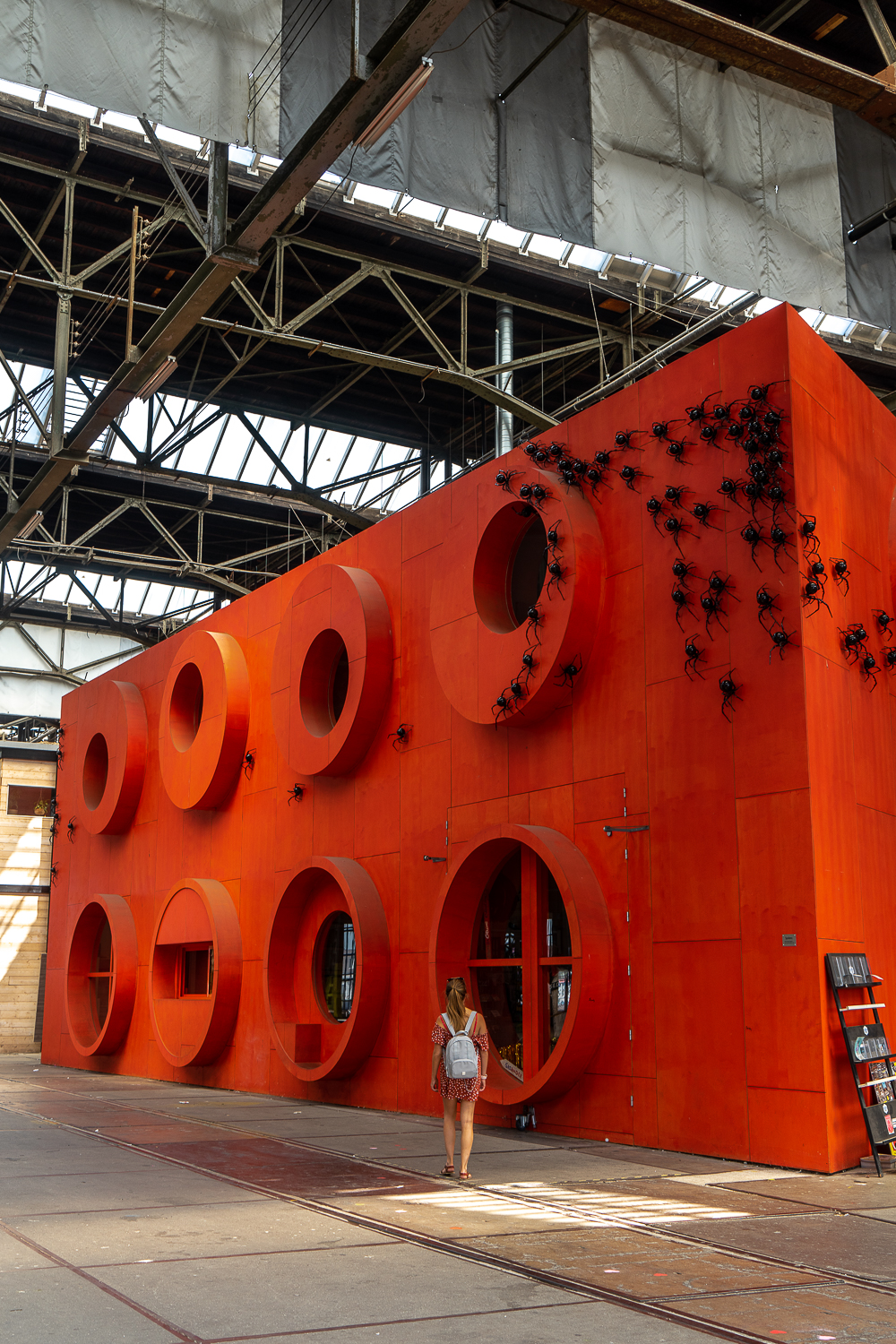 A giant lego brick with spider sculptures crawling on the surface