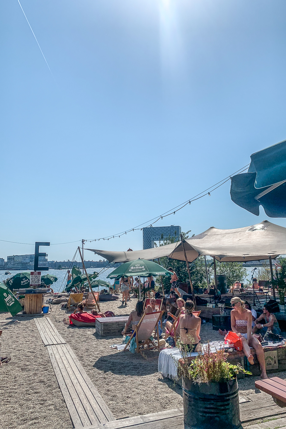 People sat in beach wear outside a bar with parasols