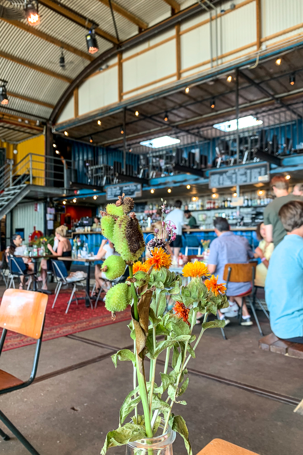 A bouquet of flowers in a vase inside an industrial looking restaurant