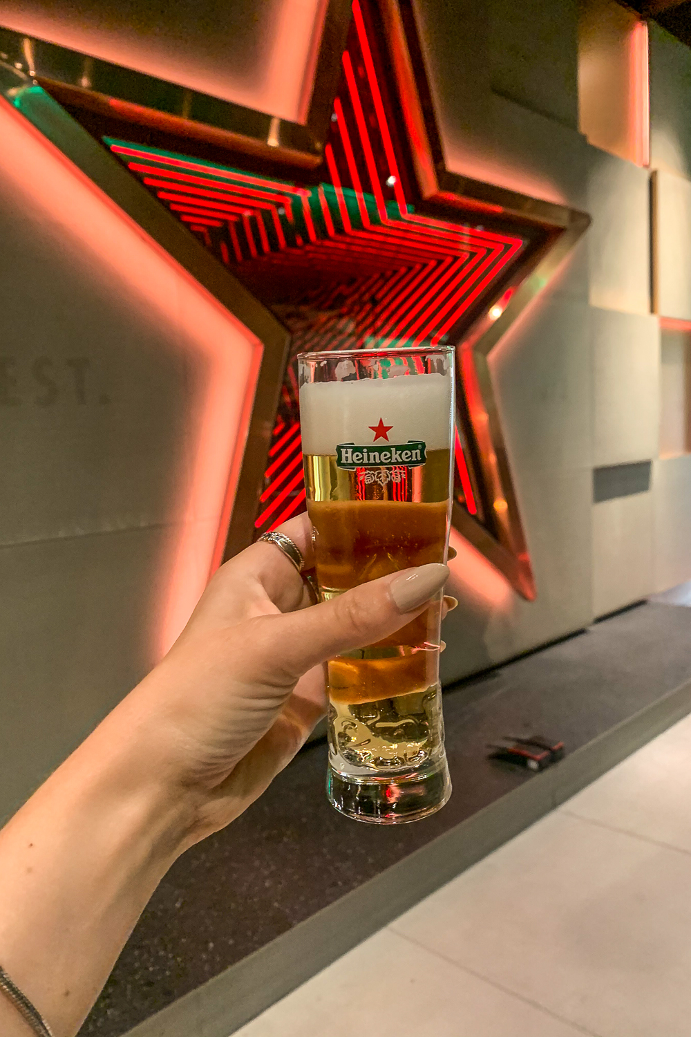 Holding a half pint of Heineken with the red star logo in the background