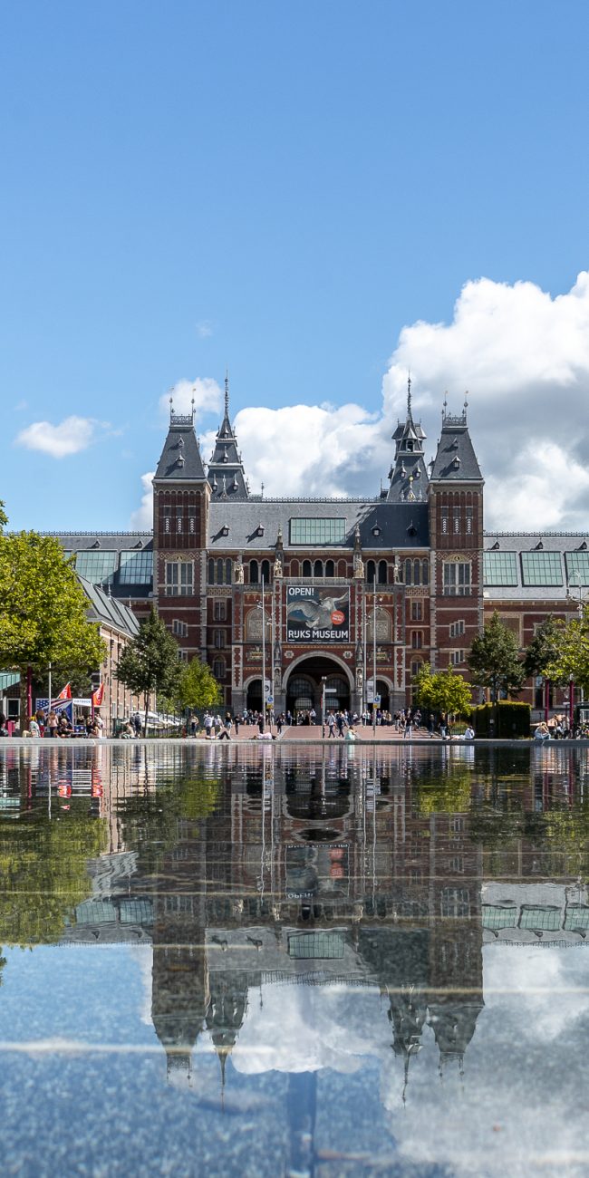 Wide view of the Rijksmuseum in Amsterdam with water and reflection in the foreground