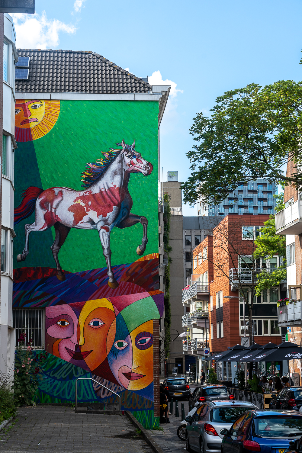 Street art of a horse on a bright green background and some strange Picasso like faces