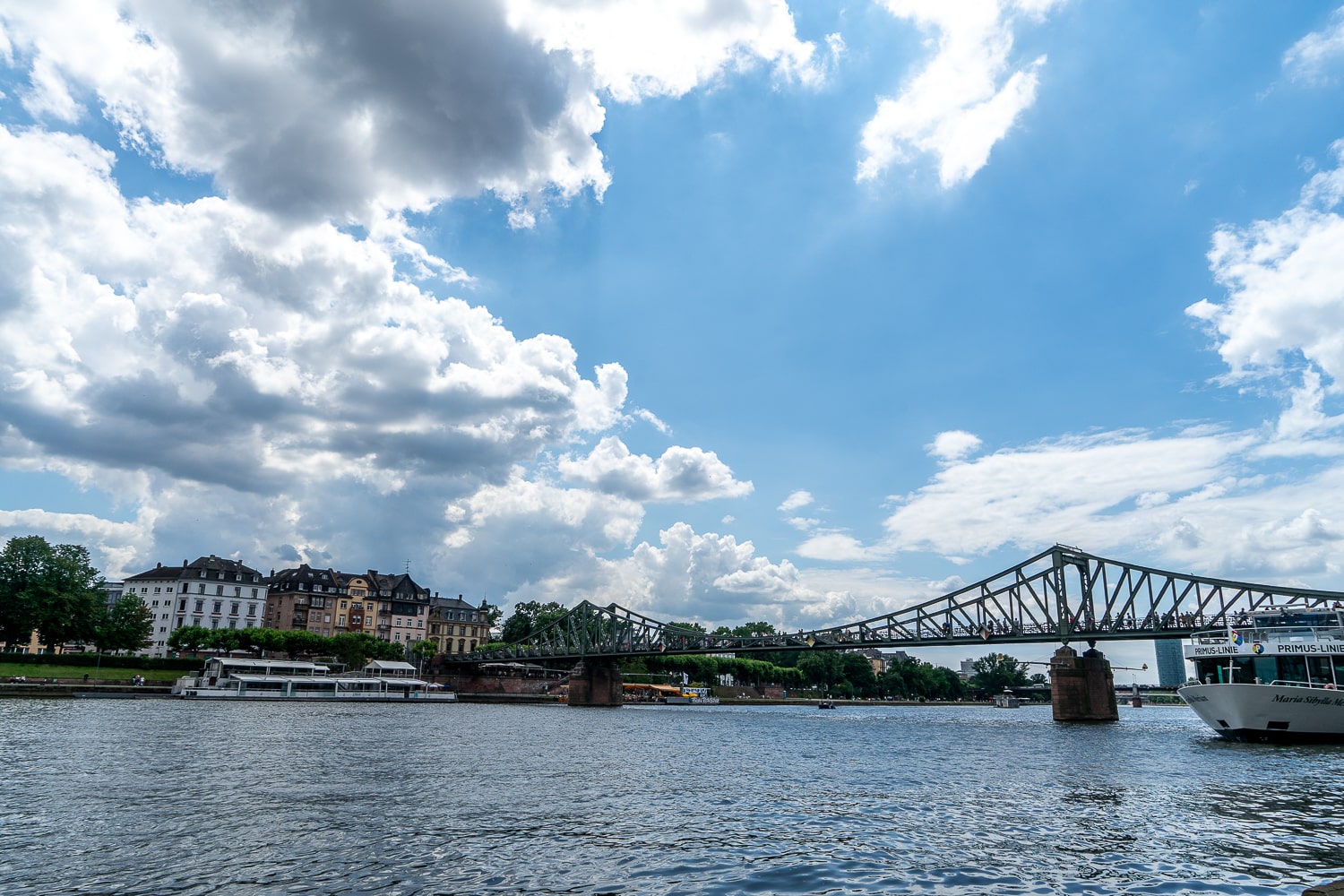 A landscape shot of the river in Frankfurt with an old iron bridge in view