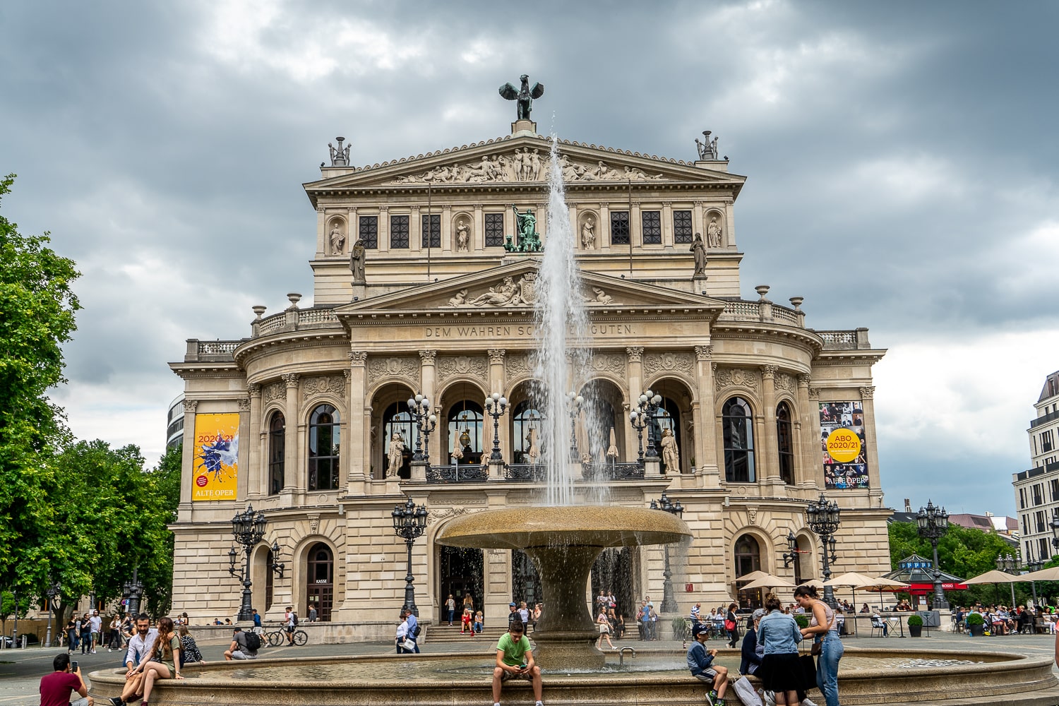 A large opera house in cream coloured stone with a large fountain in front