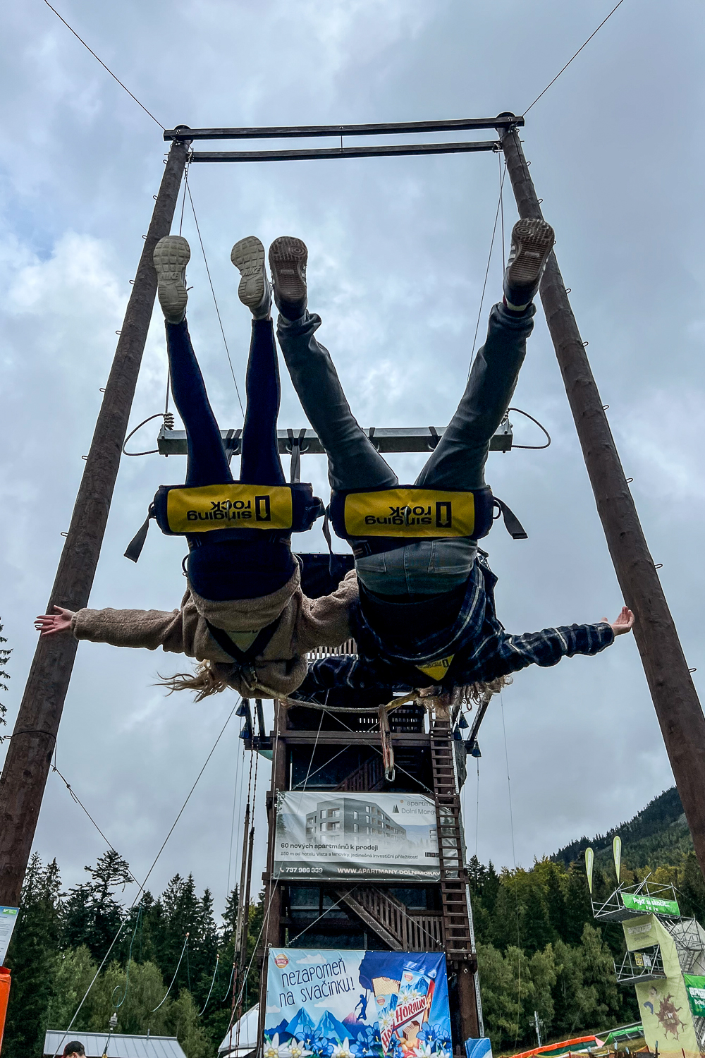 A couple upside down on a huge swing