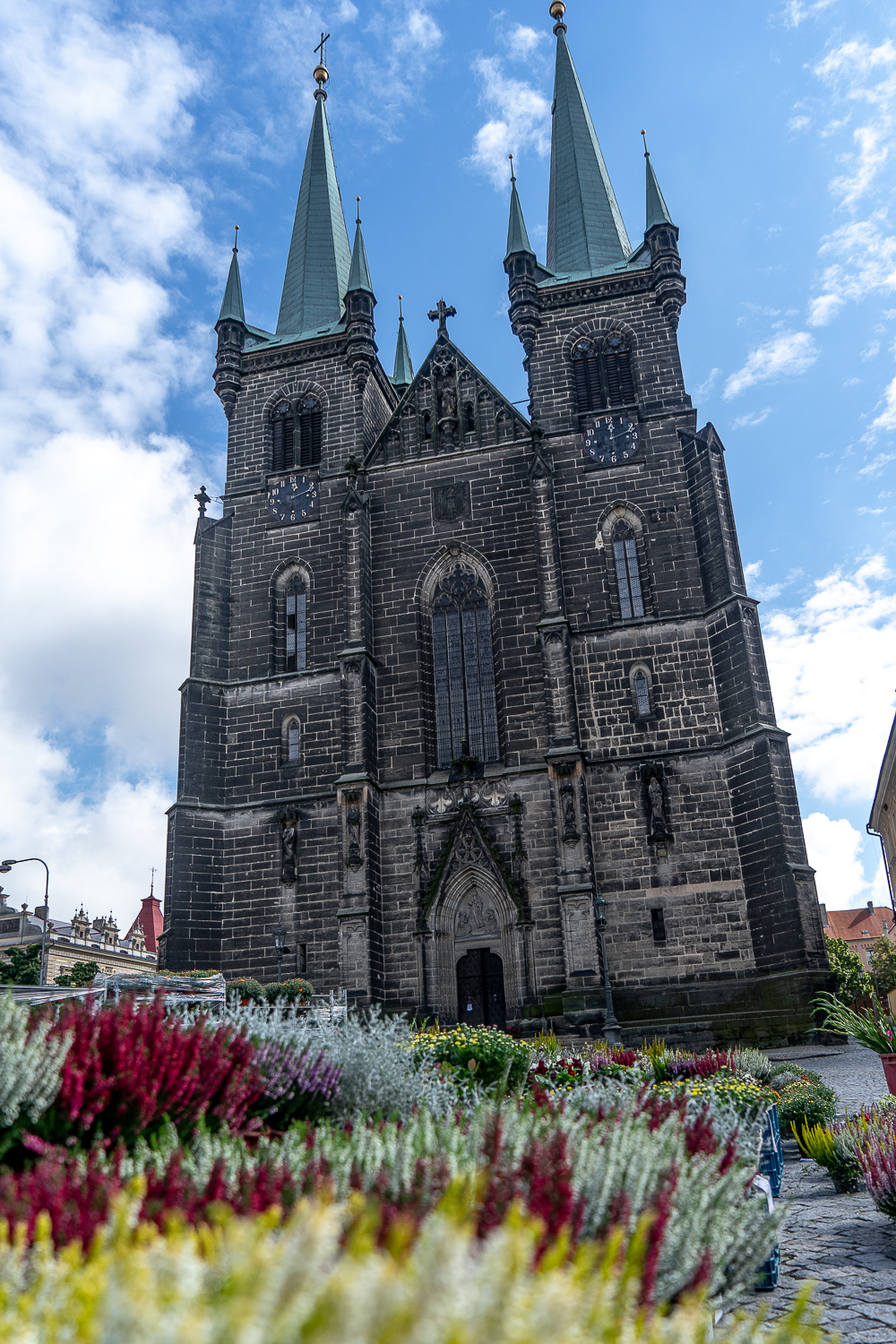 A double spired church with flowers in the foreground