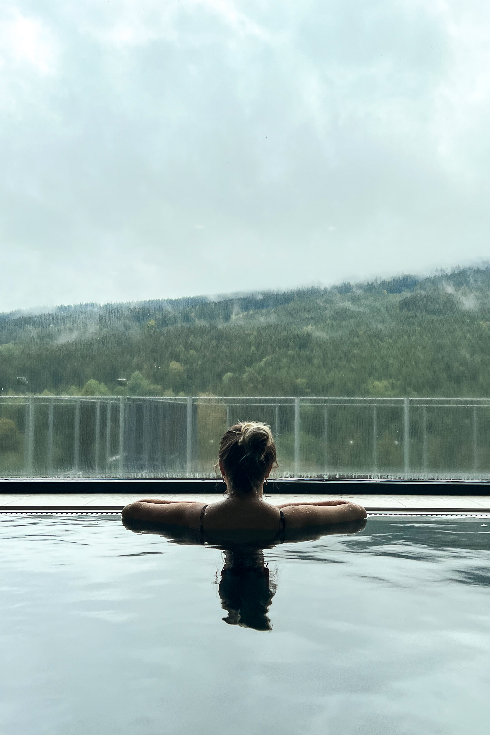 A girl looking out to the forests from the pool