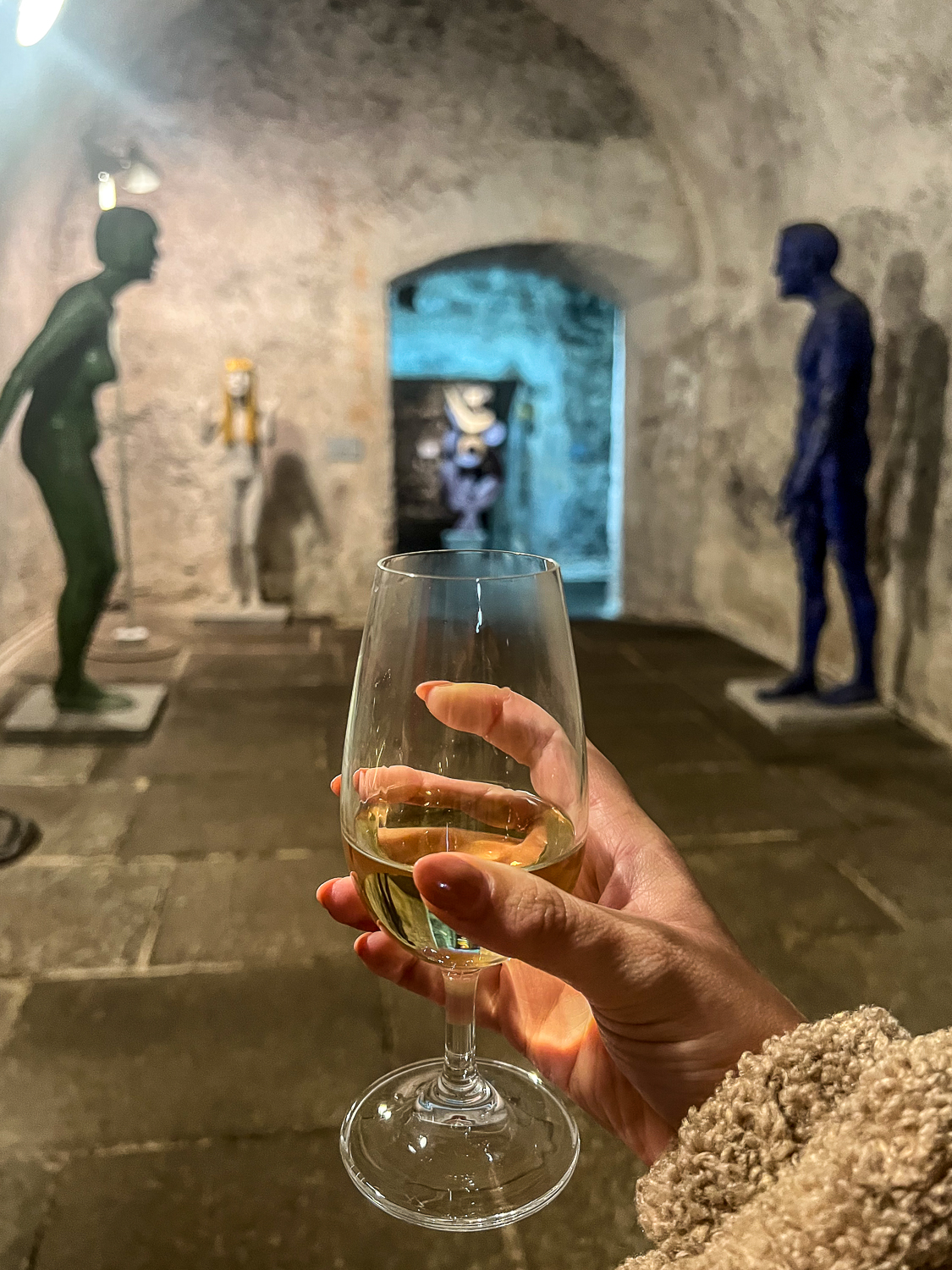 Girl holding a white wine in a castle wine cellar