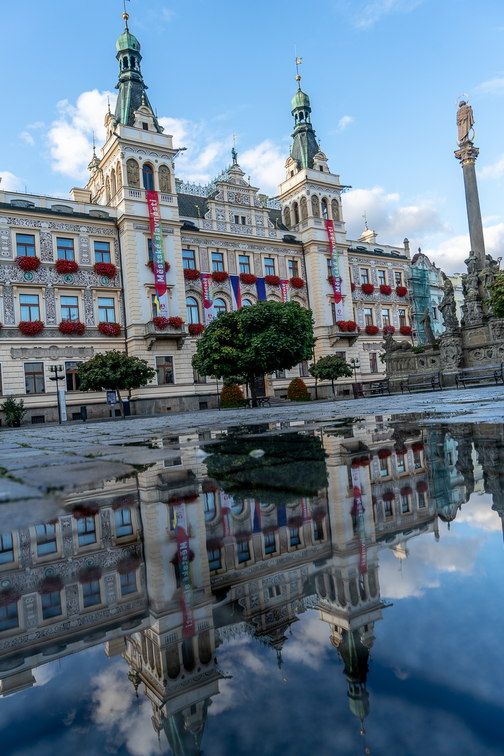 Pardubice town hall reflected in a puddle on the street