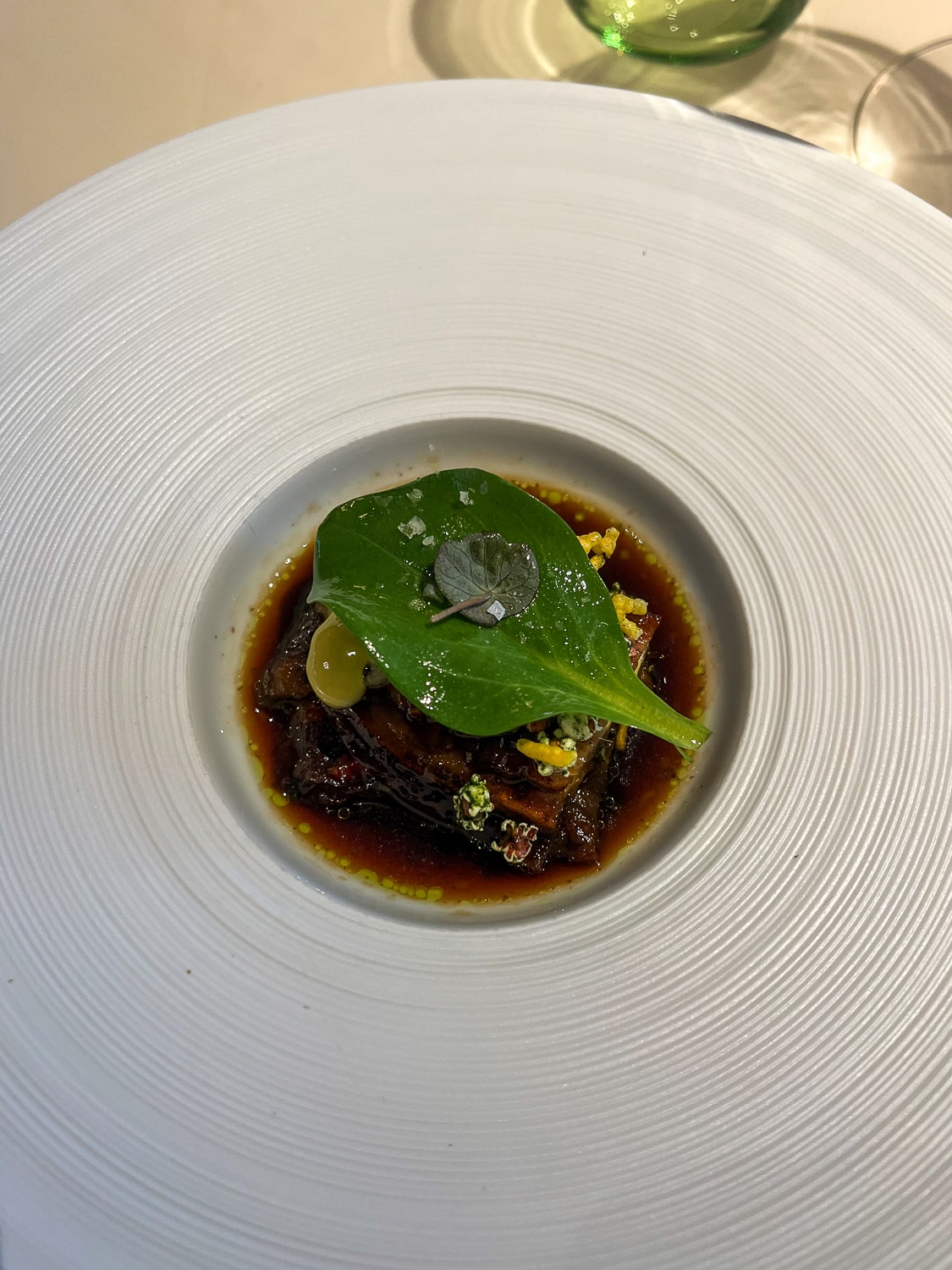 An aubergine dish in a fine dining restaurant served in a wide rimmed white bowl