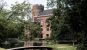 A red brick castle with a small bridge crossing the moat amongst trees