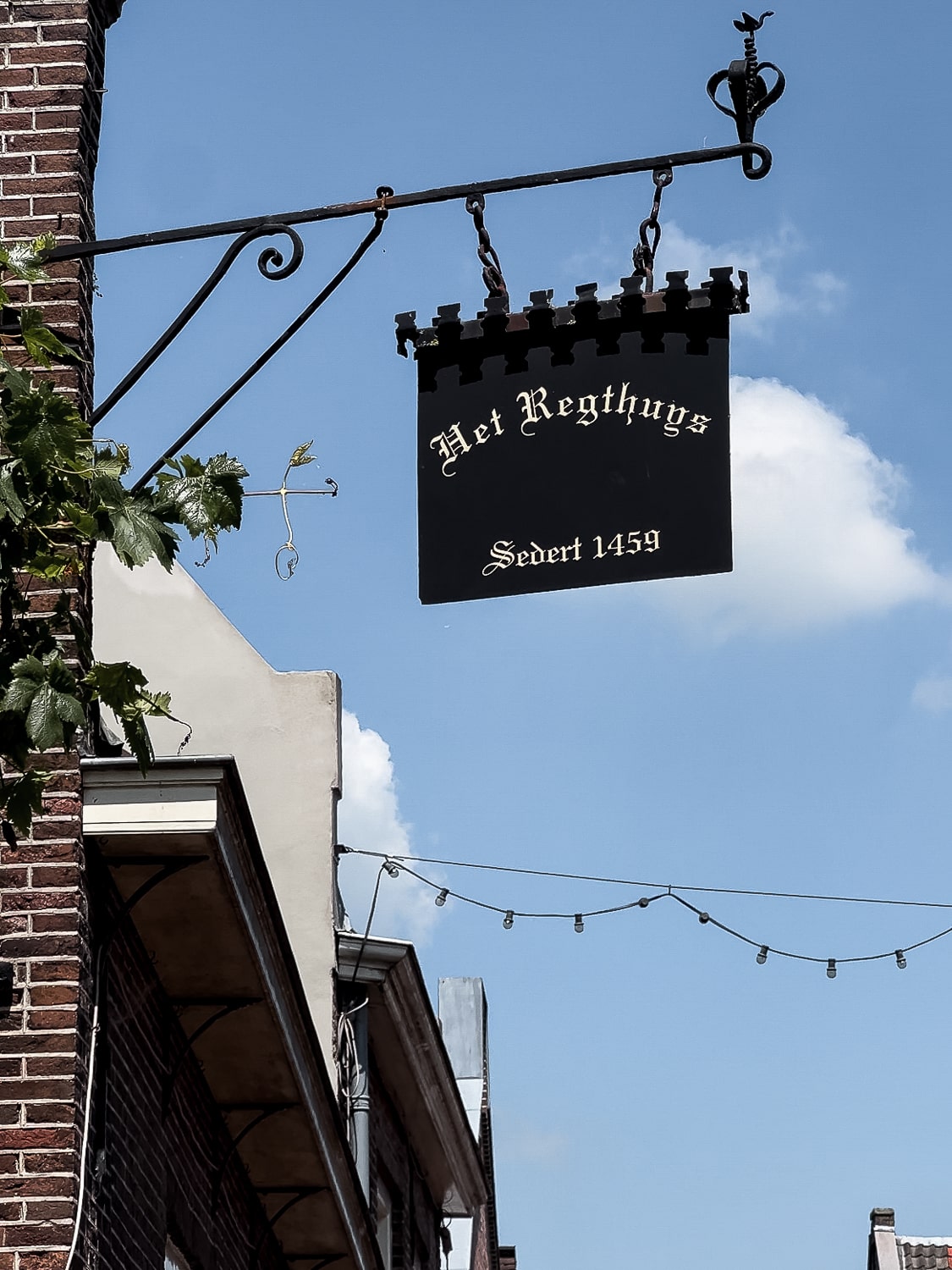 A brown brick building with a sign reading 'Het Regthuys'