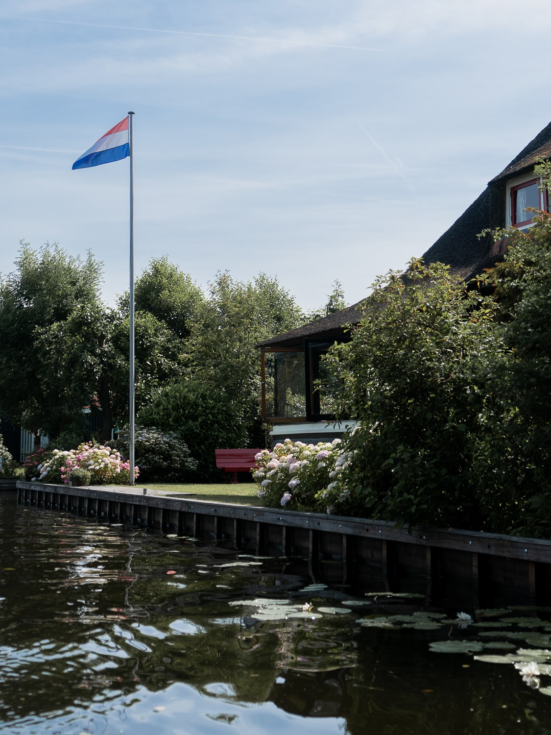 A lake house in the Netherlands with a Dutch flag on a flagpole