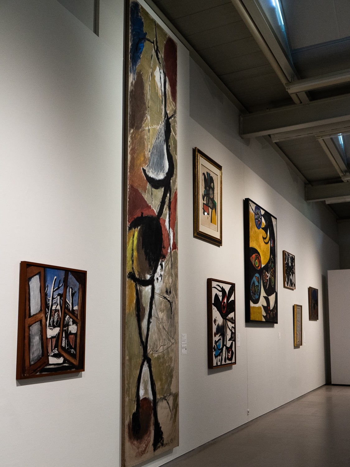 An art gallery wall with several colorful, abstract paintings hanging