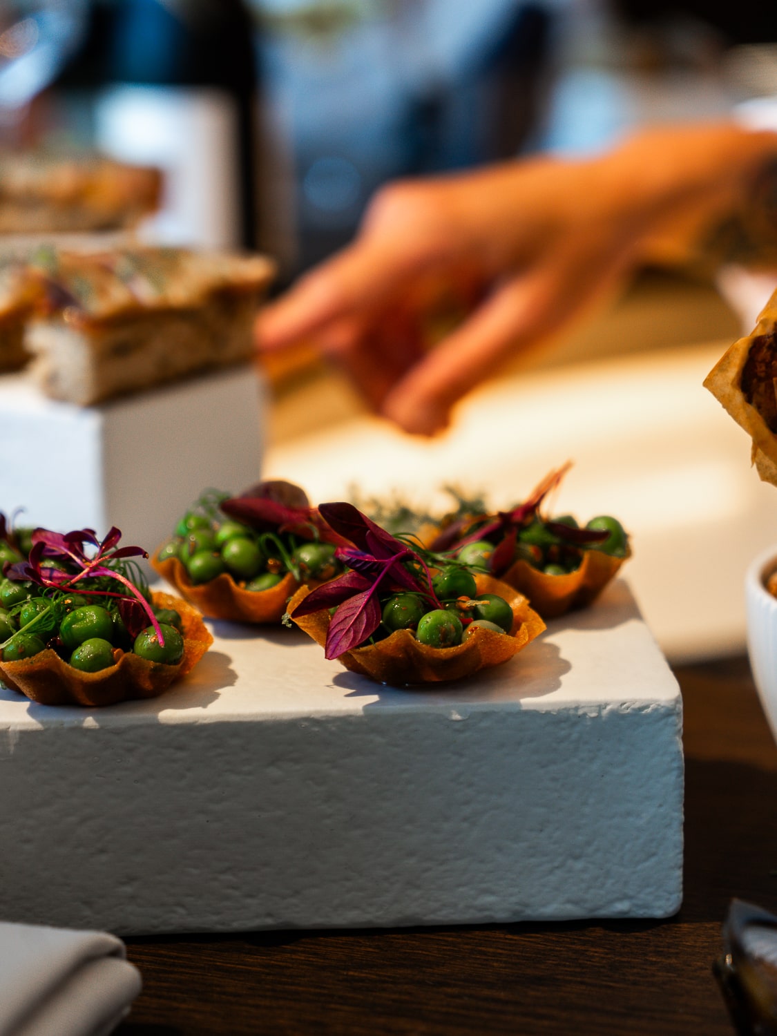 Several apetizers made of a pastry casing with peas and other colourful ingredients