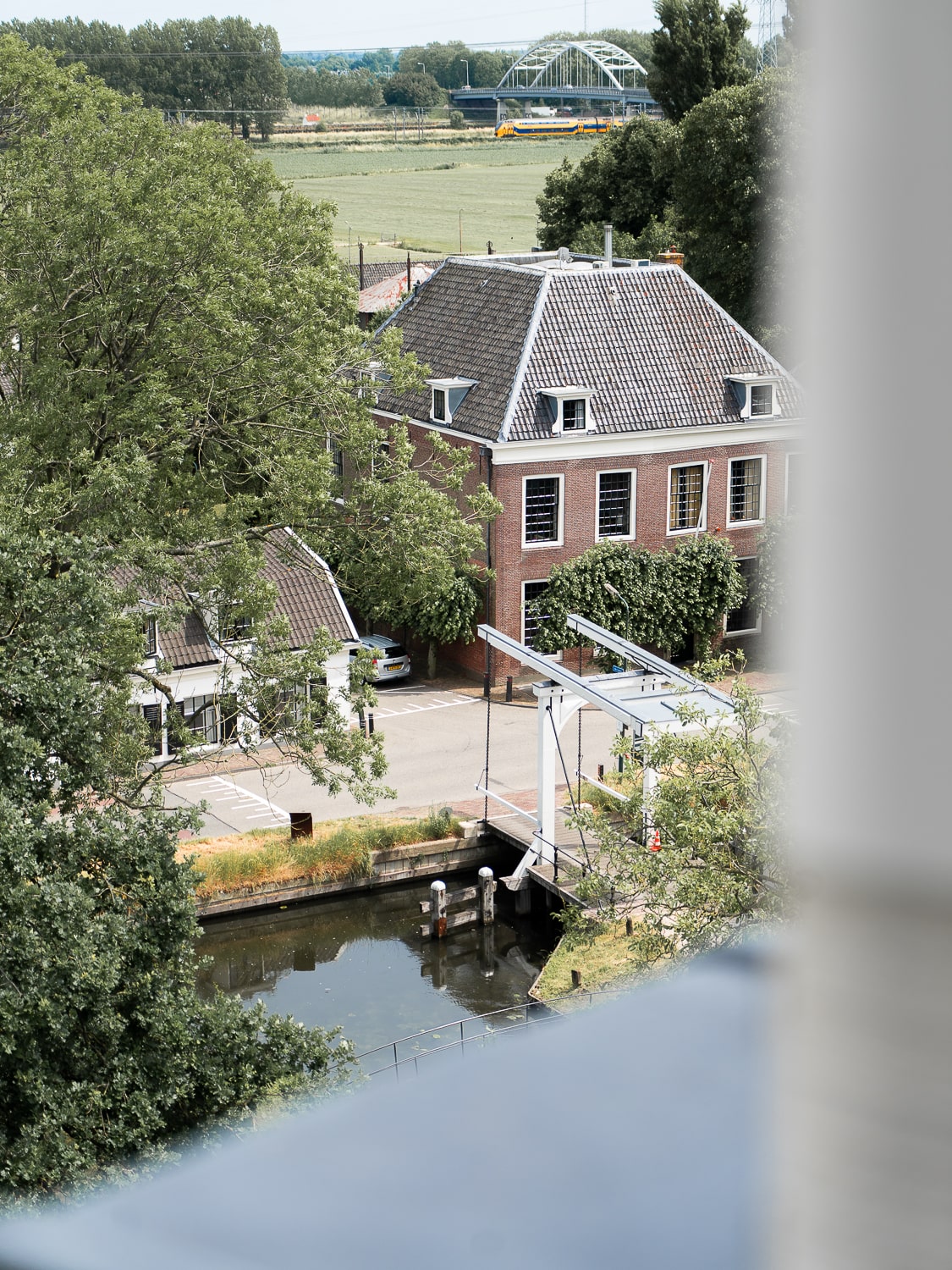 A view from a castle tower of the moat, small river with a manual drawbridge and a nearby country house