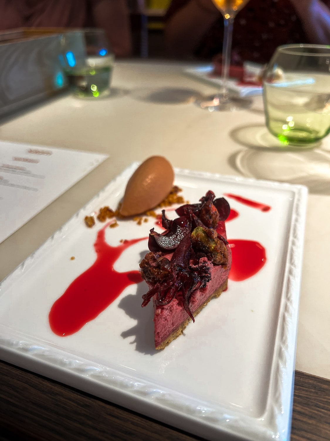 A colourful, pink and red cheesecake with tropical sorbet in a fine dining restaurant