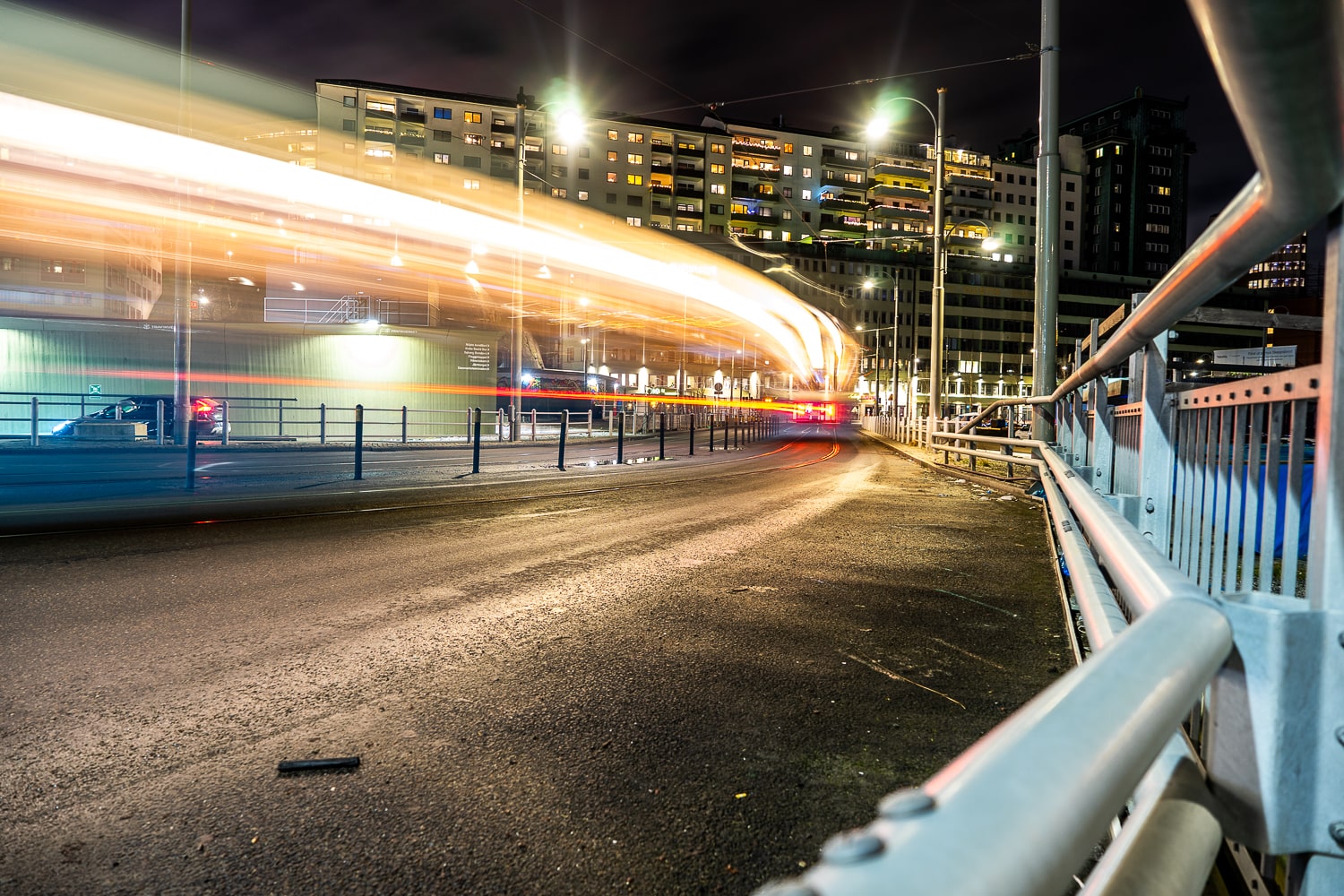 A long exposure shot of a tram moving through the streets of Gothenburg at night with long streaks of white and red light
