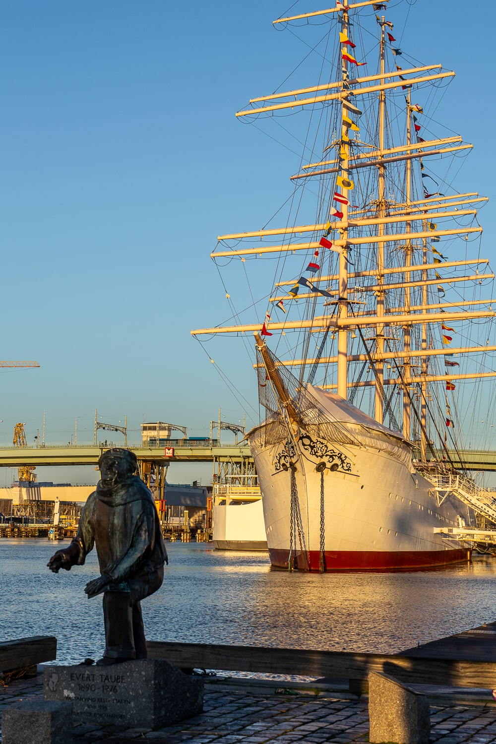 A huge sailing ship docked at a port with a statue of a fisherman in the foreground. A symbol of Gothenburg's history as a seafaring city