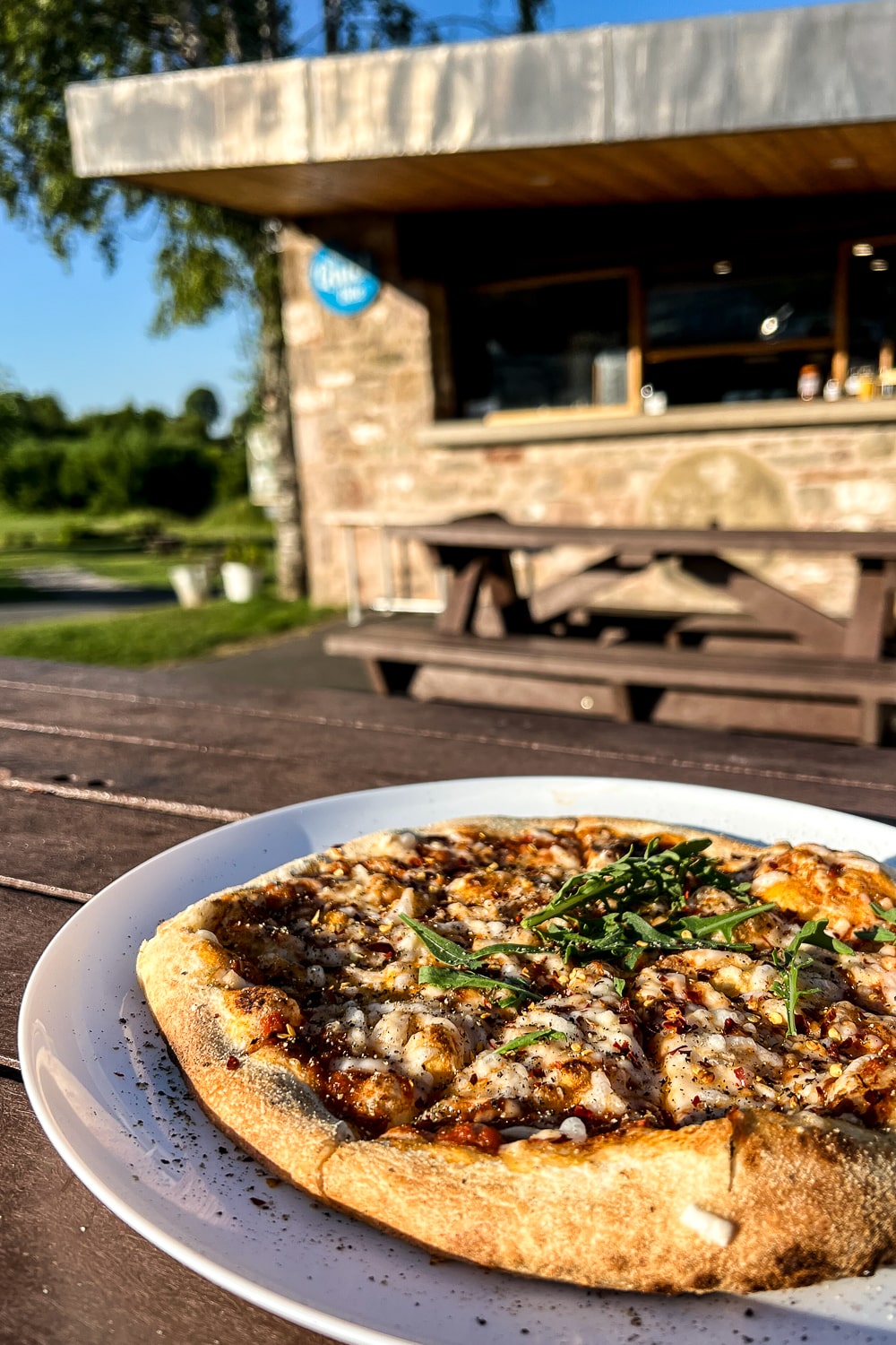 A pizza on a plate on a picnic bench