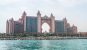 The Atlantis Hotel in Dubai from the water. A grand hotel with pink coloured stone and a large keyhole shape in the center of the building