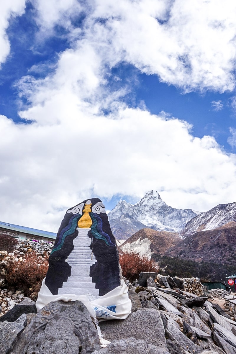 A rock with a gold and white painted stupa carved into it