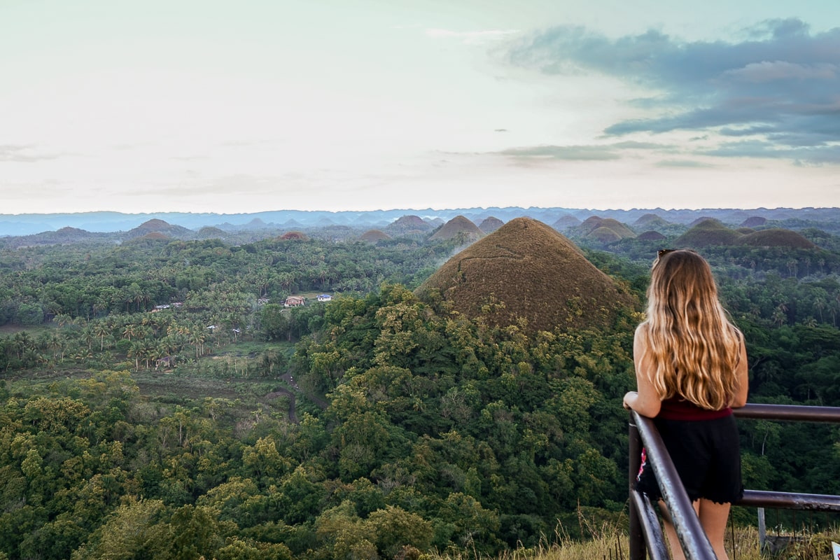 A woman looking out over the chocolate hills in Bohol - a series of brown pointed hills