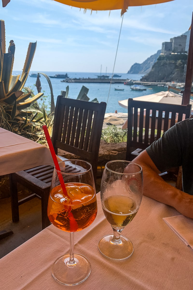 A view of the sea from a restaurant, an aperol spritz and a beer on the table in the foreground