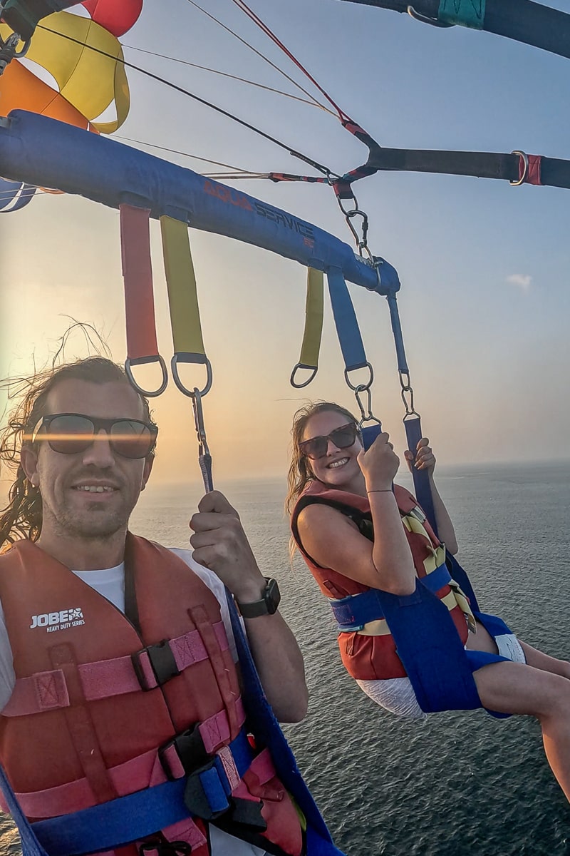 A couple parasailing at sunset over the ocean