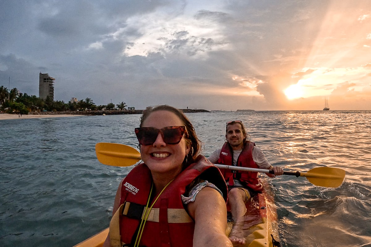 A couple kayaking on a yellow kayak with yellow oars at sunset