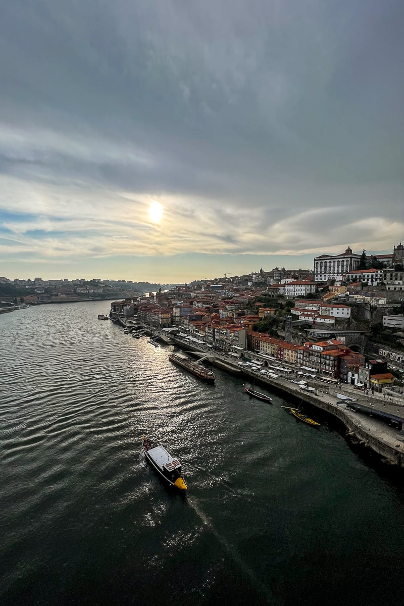A boat cruising on the river Duoro past the Ribeira district with red rooves