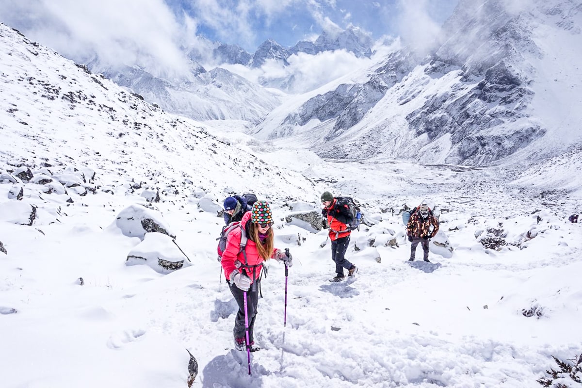 A group hiking through glistening snow on a very bright day on the way to Everest Base Camp