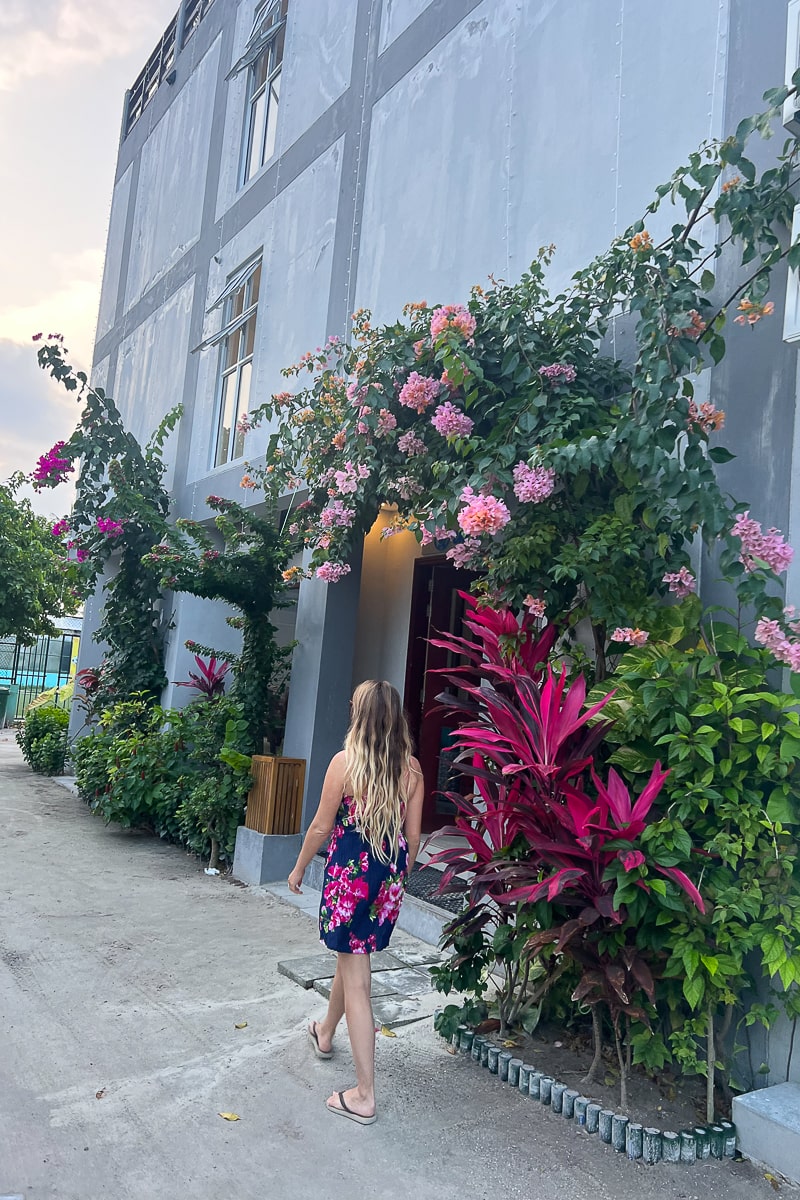 A person walking past a wall covered in plants and flowers