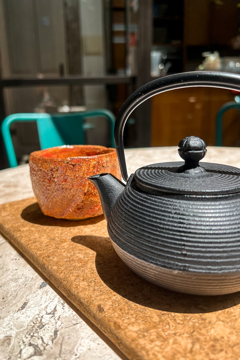 A Japanese style, black, cast iron teapot and ceramic cup