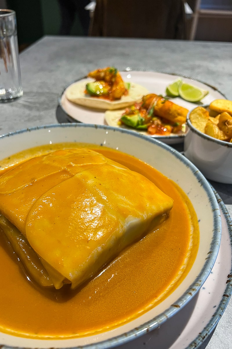 A vegan cheesy sandwich covered in an orangey gravy