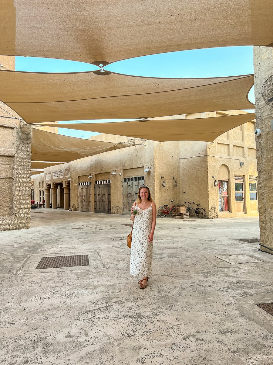 A girl standing amid sandstone buildings in the old town in Dubai