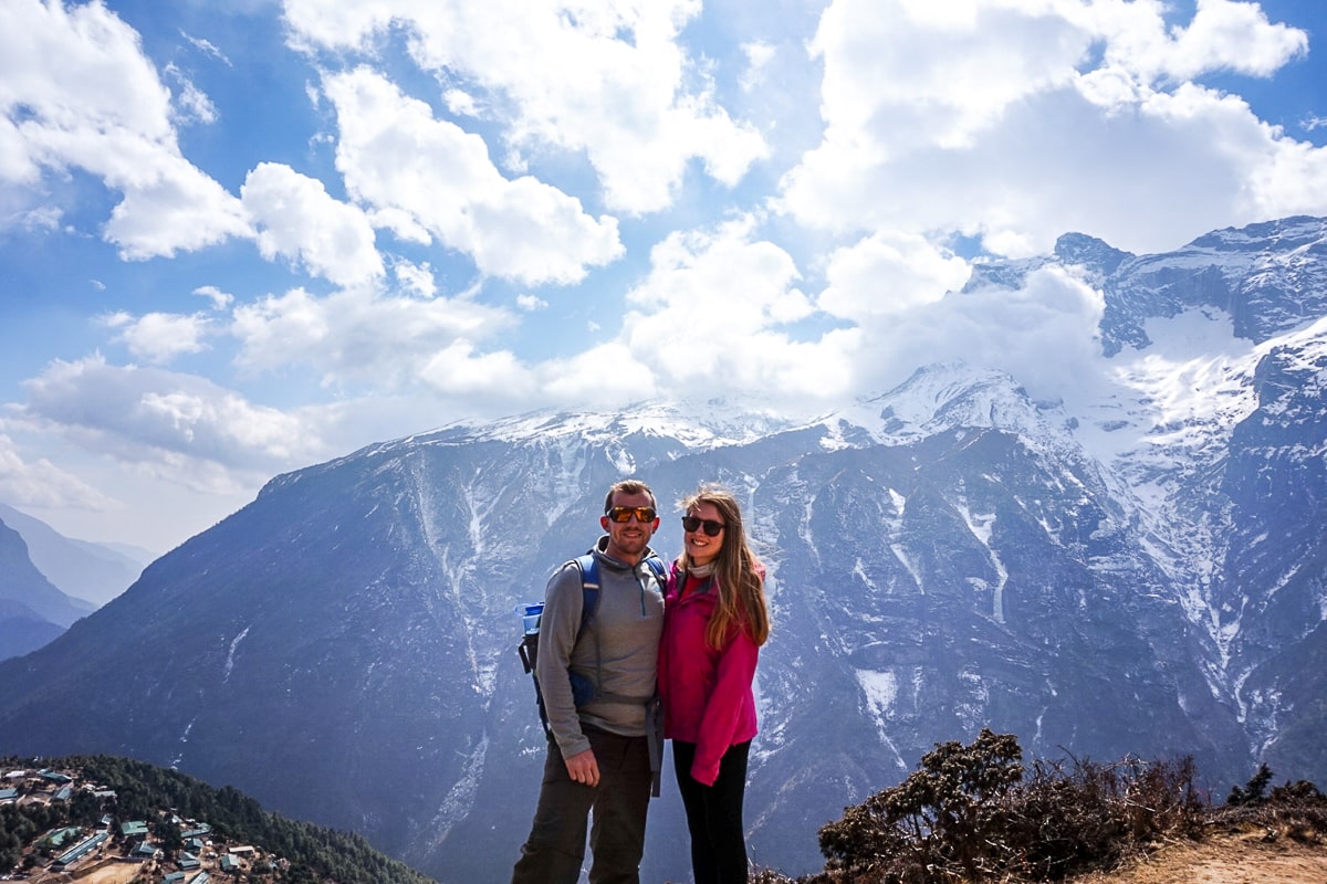 A couple stood in hiking gear with huge snowy mountains behind