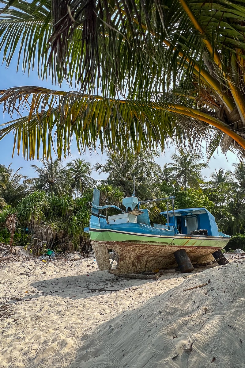 A blue and yellow boat on a makeshift drydock made from barrels and logs