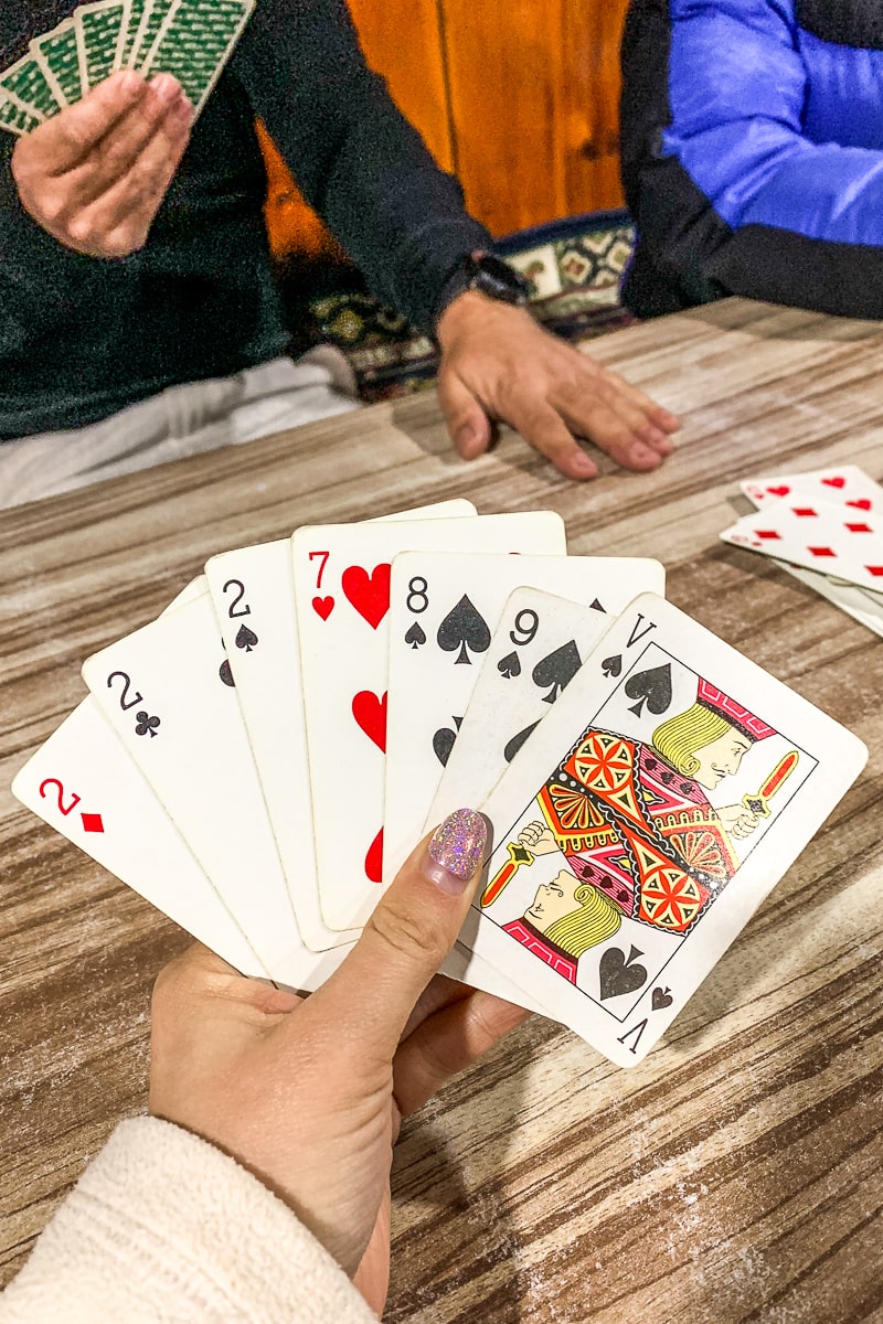 A woman with lilac nail varnish holding a hand of playing cards