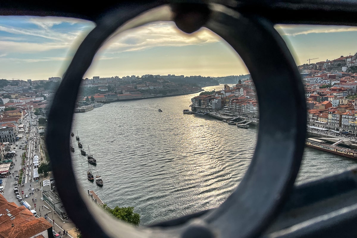 A view of the Duoro River from a high bridge through a circle in the fence