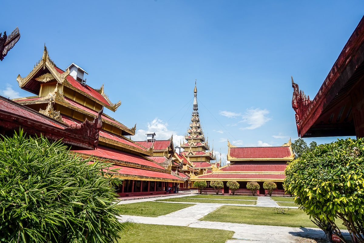A red and gold palace complex with lawns and stone paths