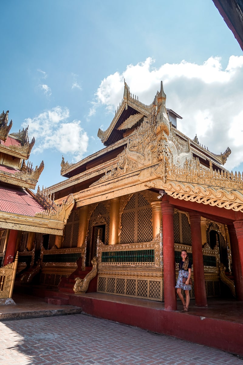 A woman leaning against a red and gold intricately carved temple