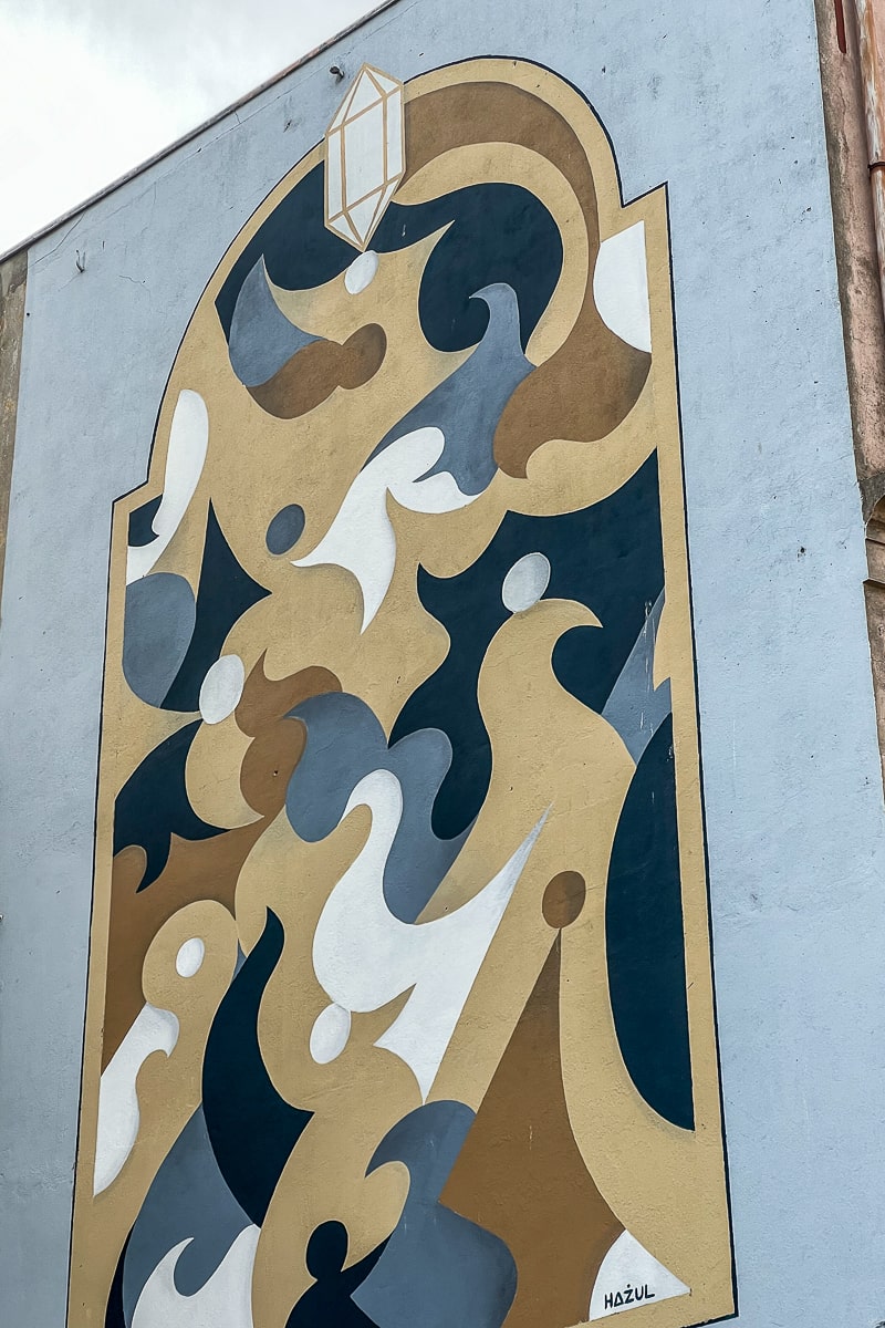 A cream, white, and blue street art in the shape of a stained window