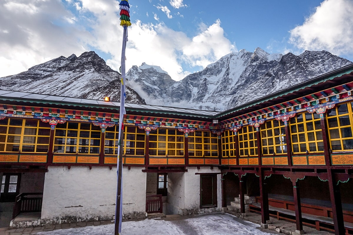 A monastery with yellow windows surrounded by snow-capped mountains