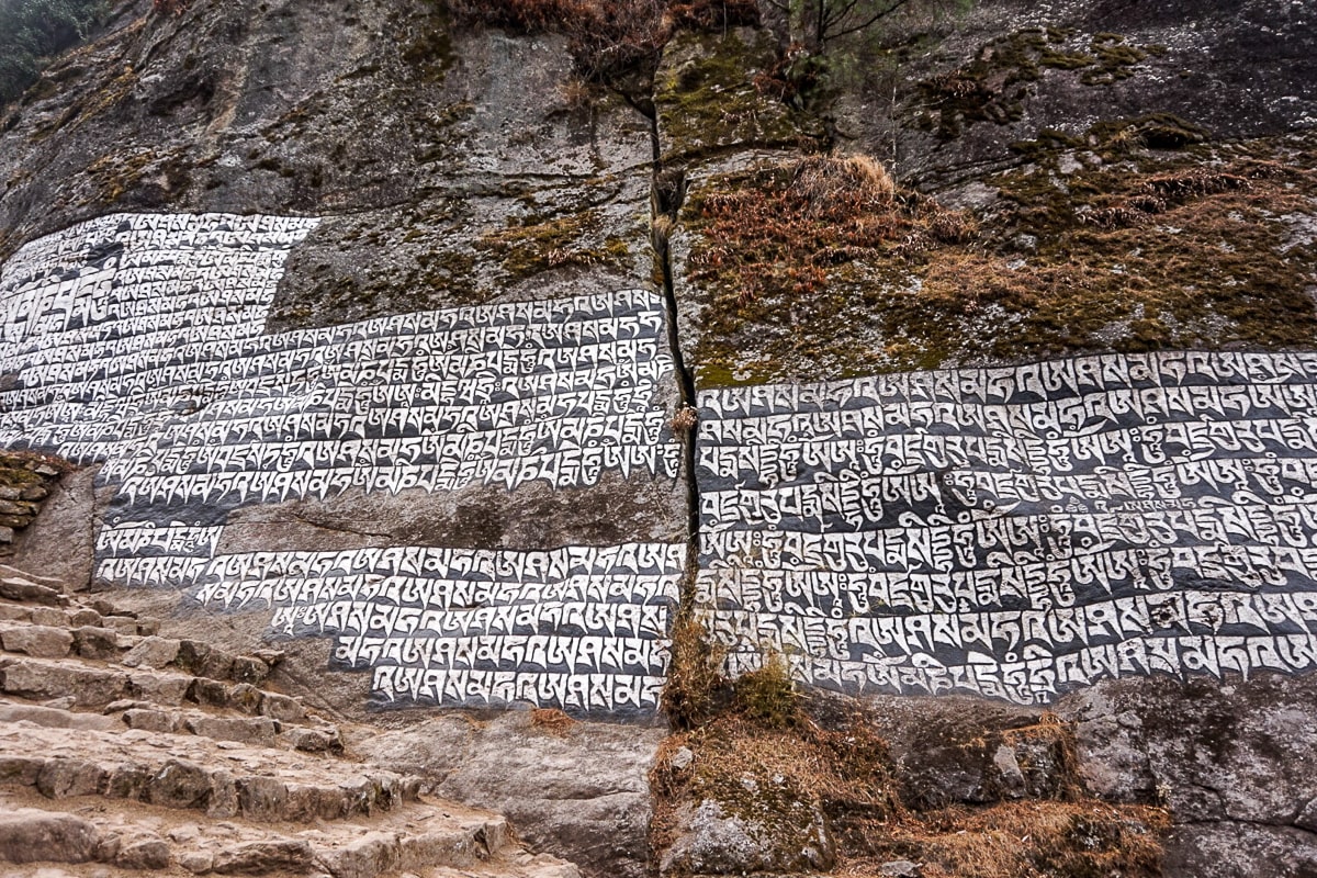 A cliff face with Tibetan symbols carved and painted